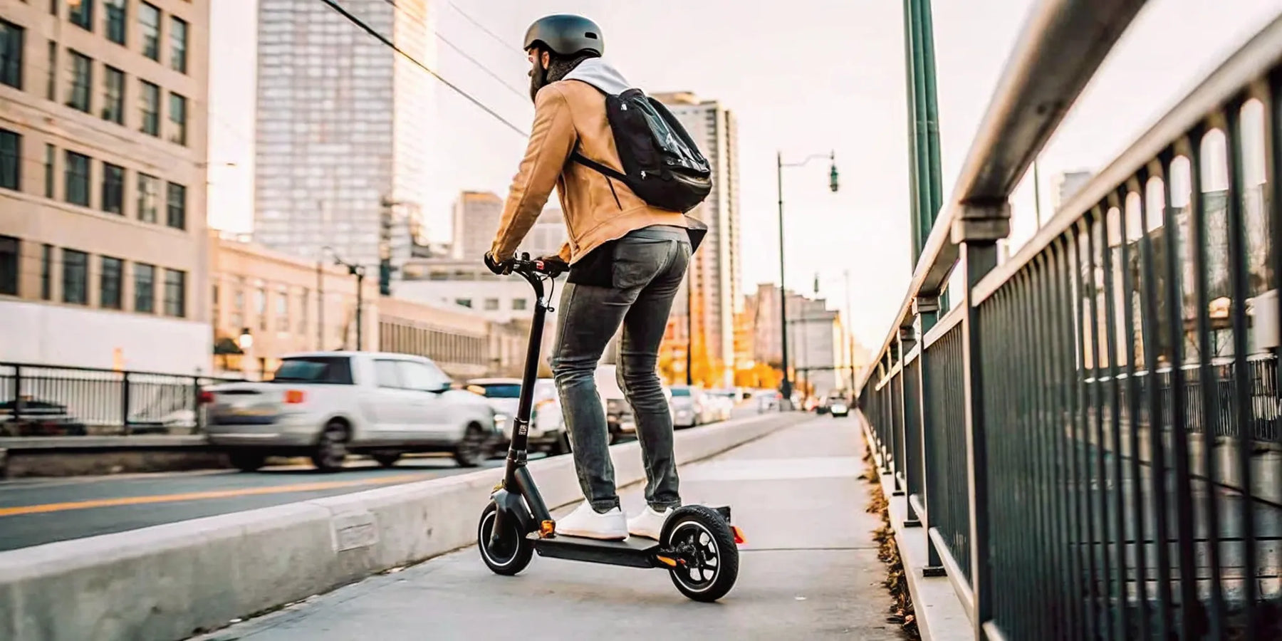 Man on the best electric scooter for commuting, wearing a helmet on a city street.