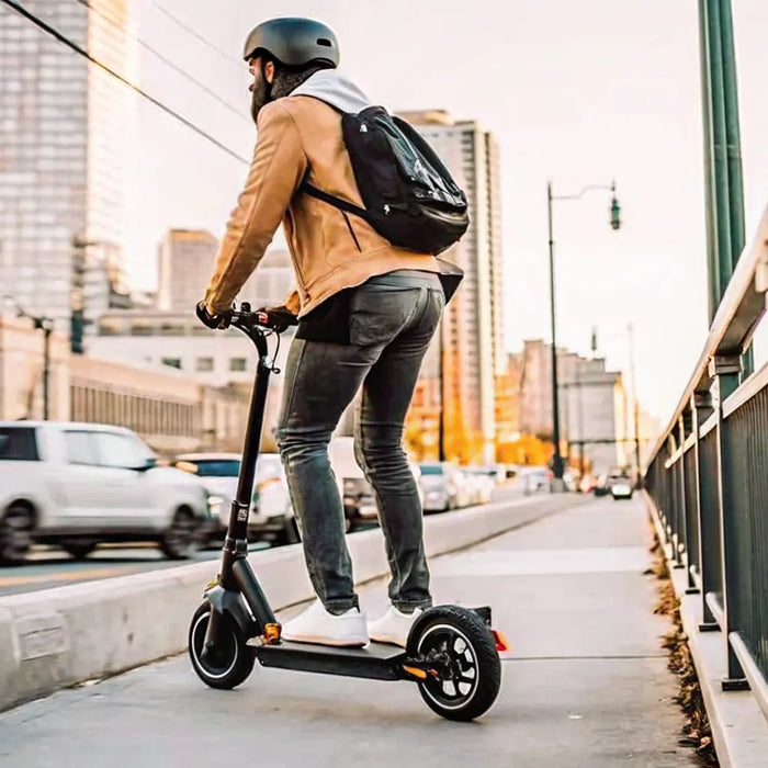 Man on the best electric scooter for commuting, wearing a helmet on a city street.
