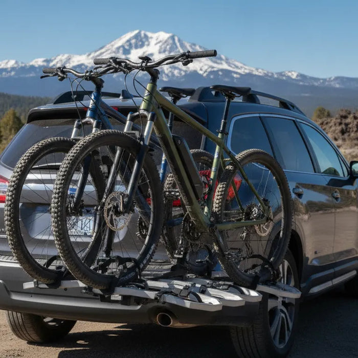 Two electric bikes secured on a hitch platform carrier behind an SUV