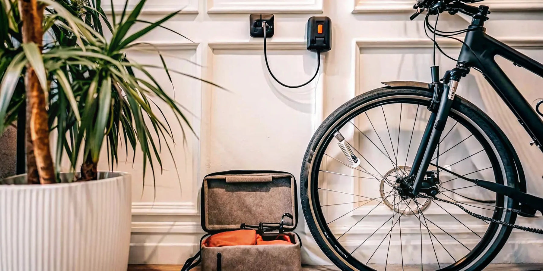 An e-bike battery charging from a standard wall outlet with its included charger.