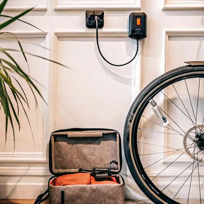 An e-bike battery charging from a standard wall outlet with its included charger.