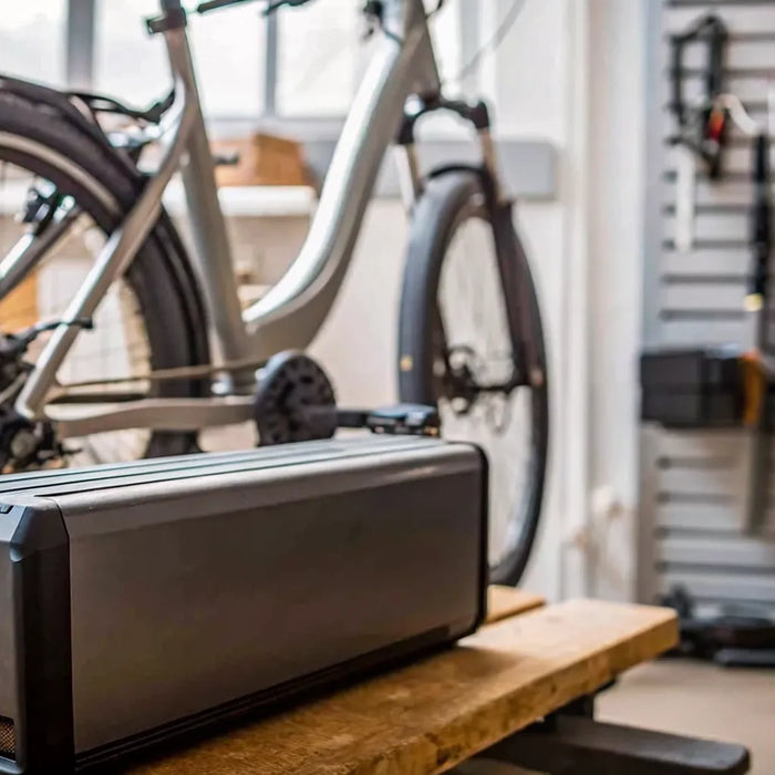 E-bike battery pack on a workbench beside an electric bicycle in a Bend bike shop
