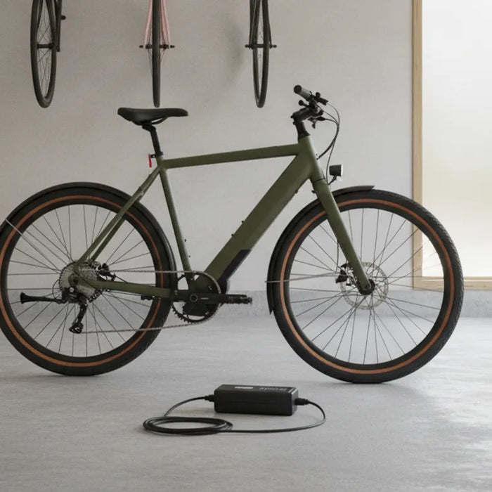 Electric bike battery and charger set up on a clear, dry surface in a home garage