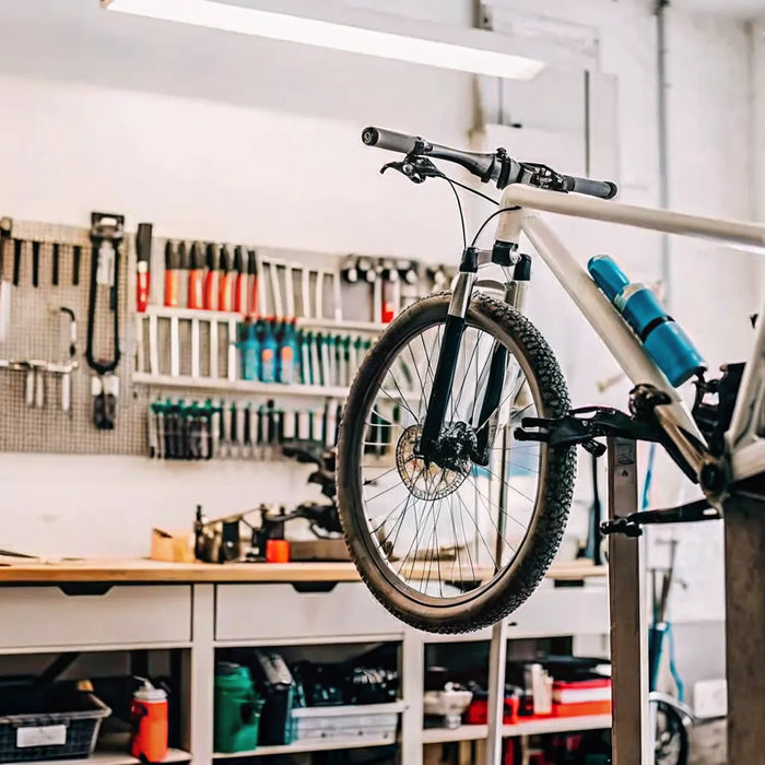Technician performing electric bike maintenance on a repair stand in a bright bike shop
