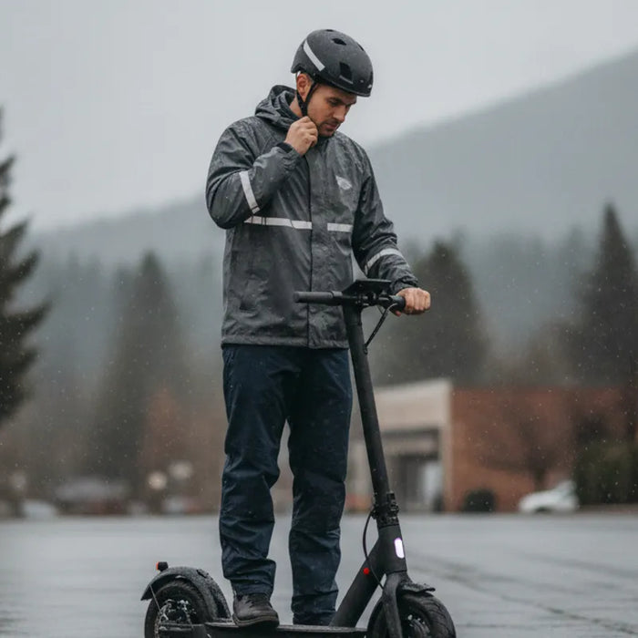 Electric scooter rider preparing for a wet ride on a Bend street
