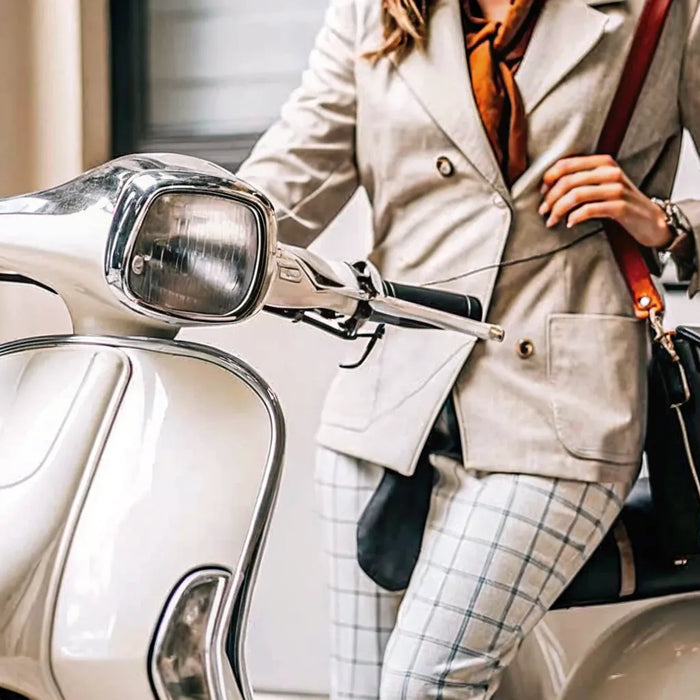 Adult in business attire sitting on a white electric scooter for sale.