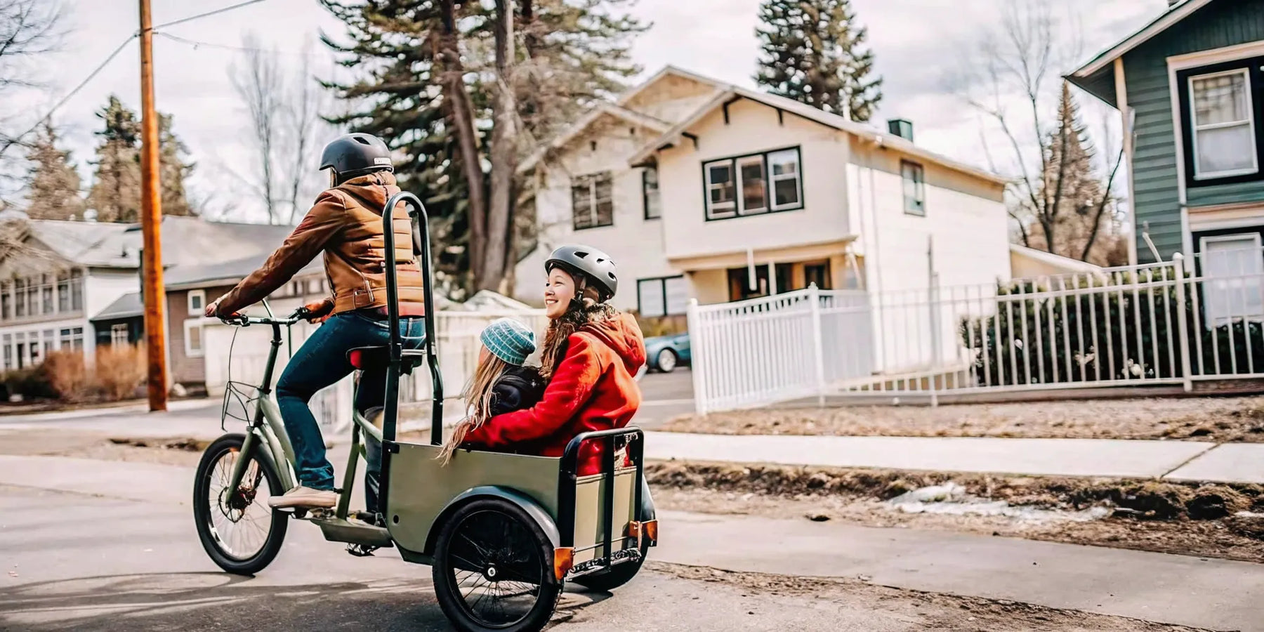 Parent riding a Segway MUXI electric cargo bike with child on rear passenger seat through a Bend Oregon neighborhood