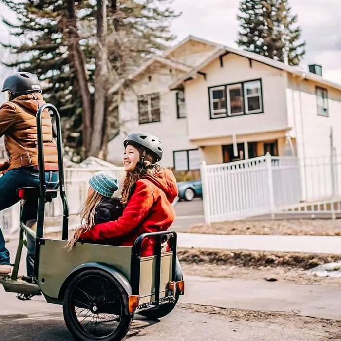 Parent riding a Segway MUXI electric cargo bike with child on rear passenger seat through a Bend Oregon neighborhood