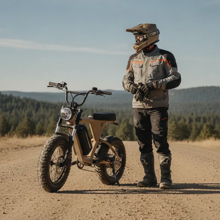 Stealth H52-style mini-moto electric bike on a wide dirt road with a rider wearing protective gear