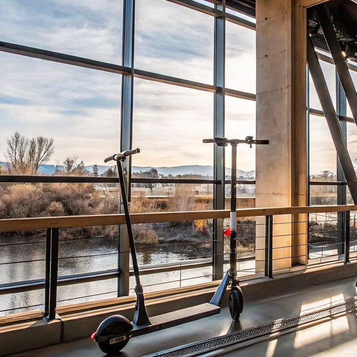A pair of electric scooters to buy in Bend, Oregon, parked with a scenic river view.