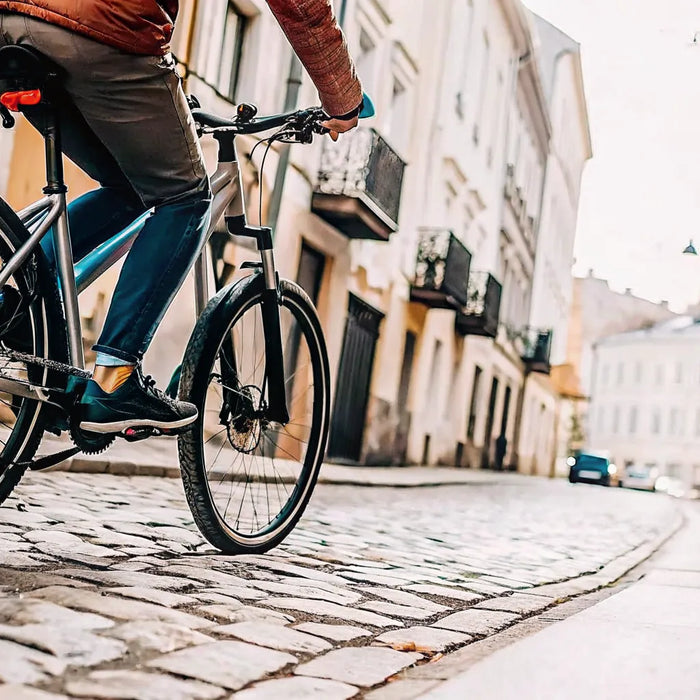 Rider on a torque sensing ebike climbing a steep cobblestone hill.