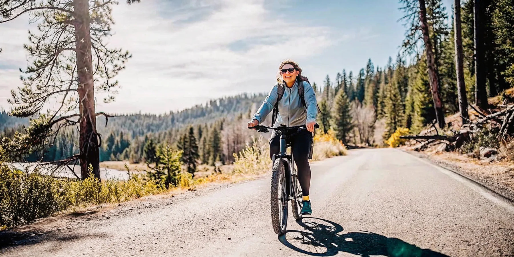 A rider on a modern electric bike gliding along a tree-lined Central Oregon trail on a bright day