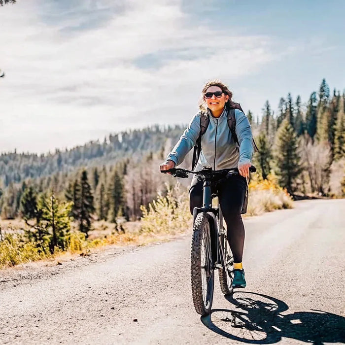 A rider on a modern electric bike gliding along a tree-lined Central Oregon trail on a bright day
