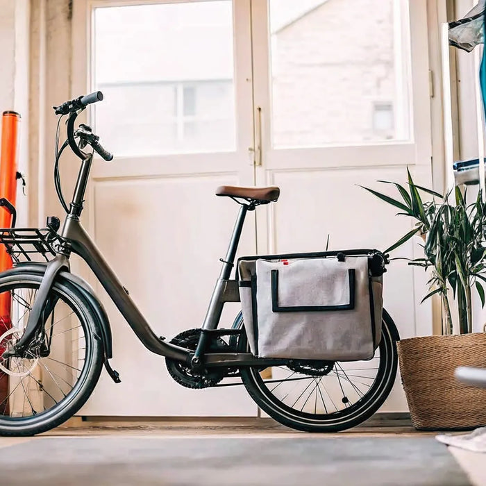 A folding electric cargo bike for adults, folded indoors to demonstrate its compact storage.