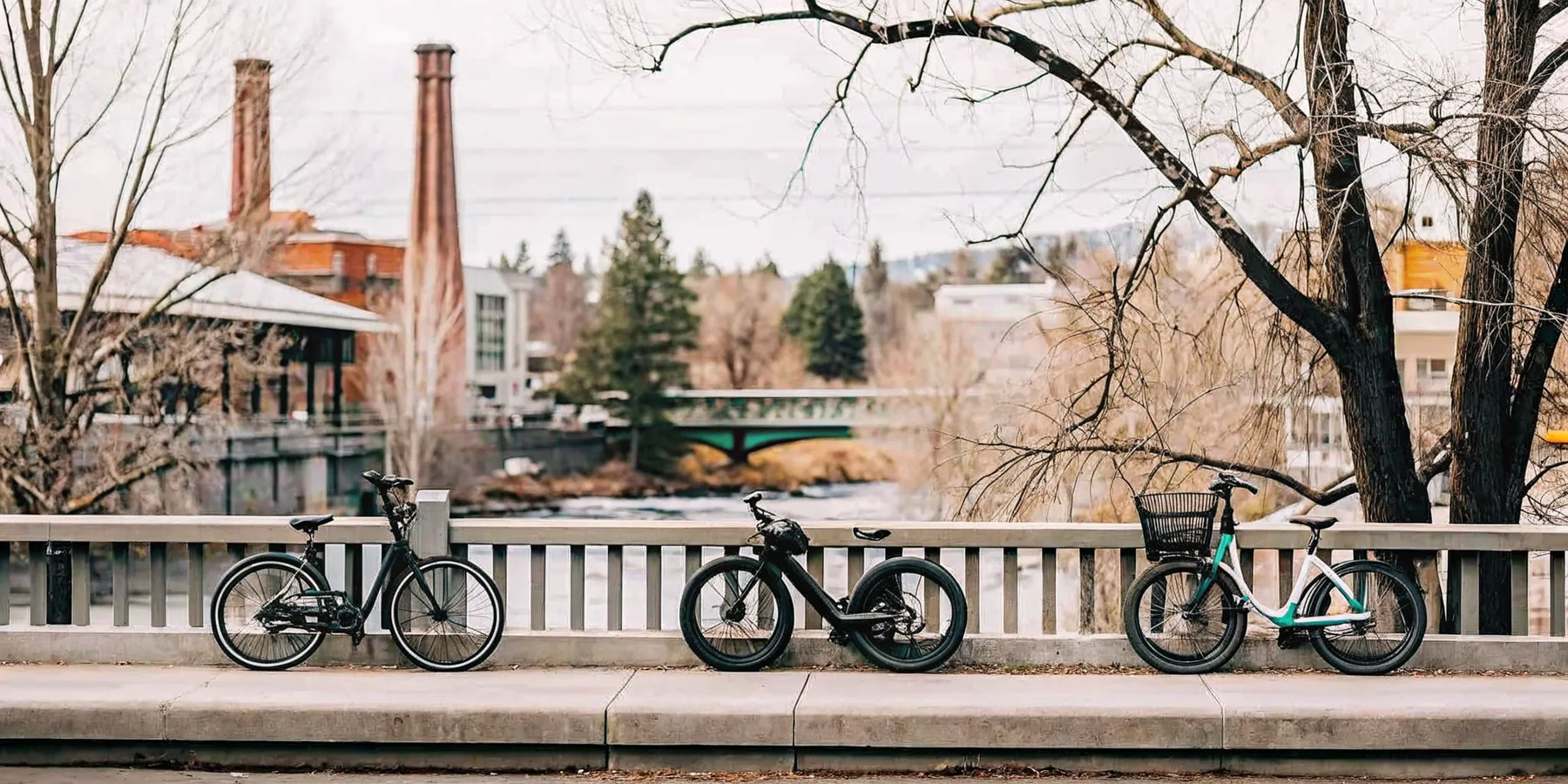 Electric trikes for sale in Bend parked on a bridge overlooking the city and river.