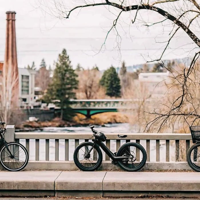 Electric trikes for sale in Bend parked on a bridge overlooking the city and river.